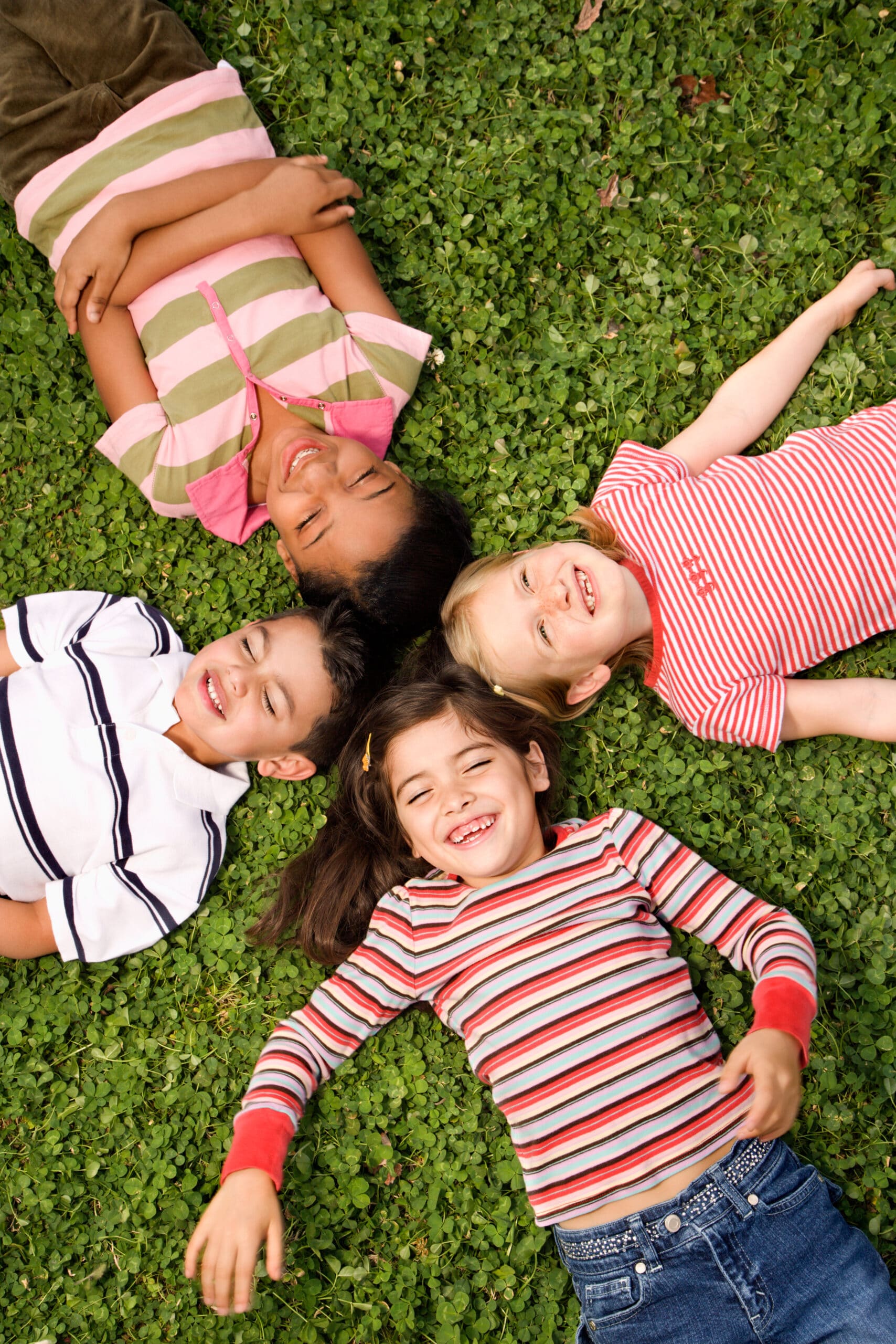 Children lying in clover with heads together.